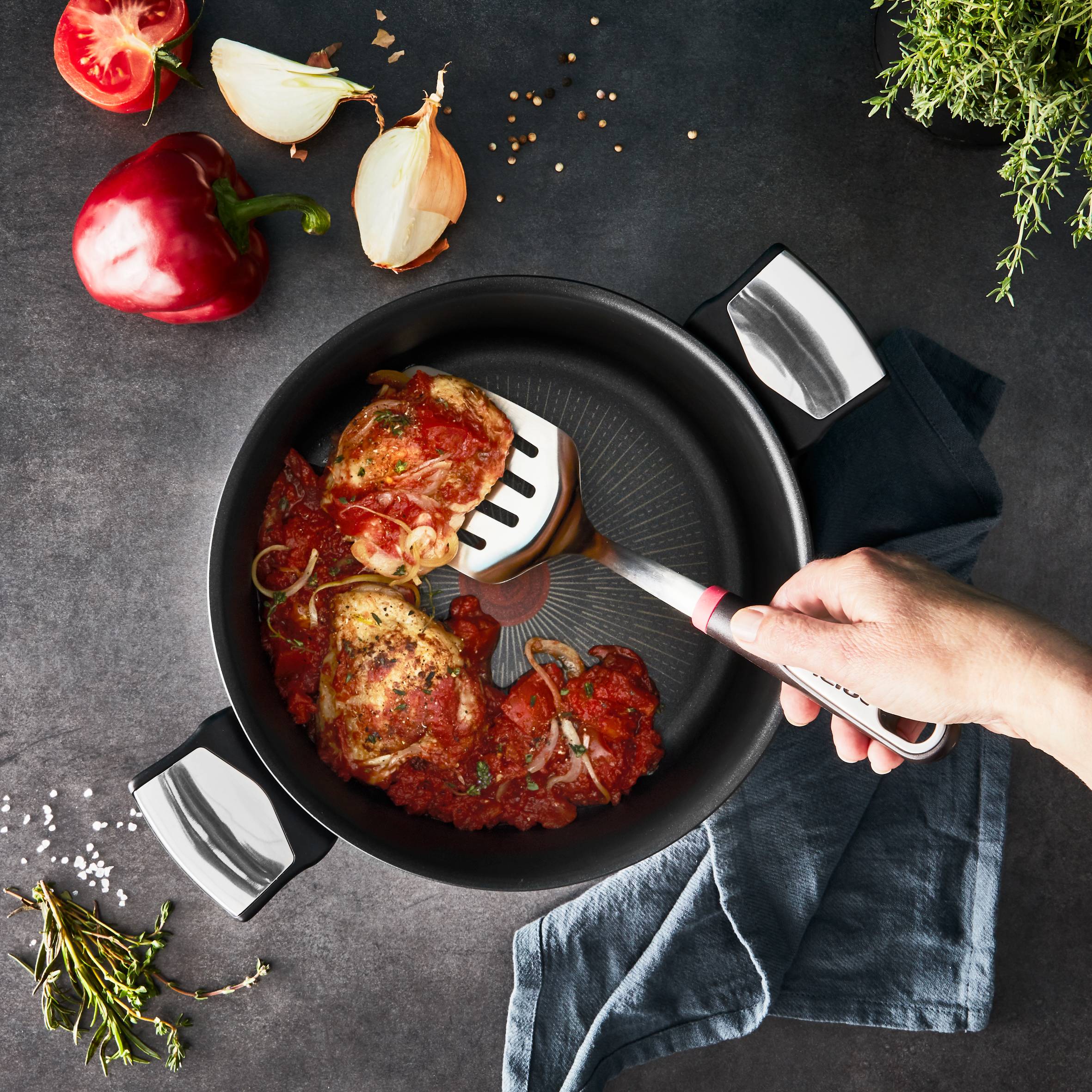 Person brät Hähnchen in Tefal Unlimited Aluminiumtopf